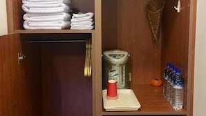 A wooden cabinet with a stack of folded towels, a coffee maker, a water dispenser, and a small refrigerator. - Chin Shan B&B (Guanshan)