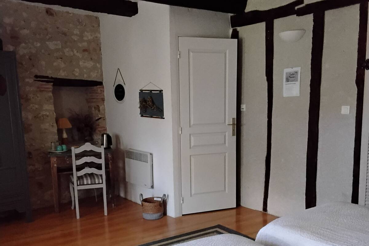 Een slaapkamer met een bed, een stoel, een open haard en een deur.