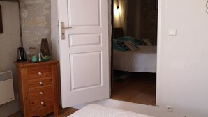 Een slaapkamer met een houten dressoir, een witte deur en een bed met gestreepte kussens.