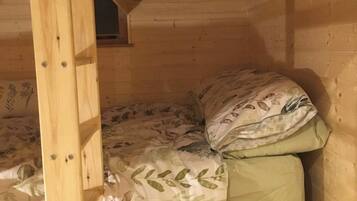 Een houten stapelbed met bloemenbeddengoed, een klein raam en een houten hoofdbord.