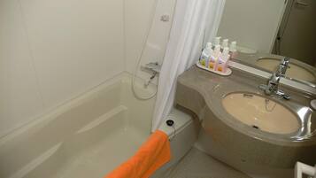 A bathroom with a bathtub, a sink, and a mirror. There are toiletries on the sink counter.