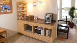 A kitchenette with a coffee maker, microwave, and storage cabinets.