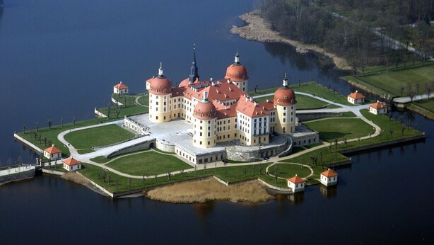 Ein großes, historisches Gebäude mit mehreren Kuppelbauten auf einer von Wasser umgebenen Insel.
