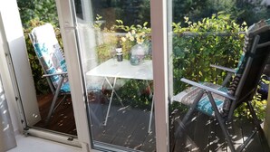 Ein verglaster Balkon mit Tisch, Stühlen, einer Weinflasche und einem Weinglas.