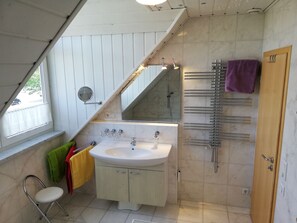 Une salle de bain avec un lavabo, un miroir, un porte-serviettes et une porte en bois.