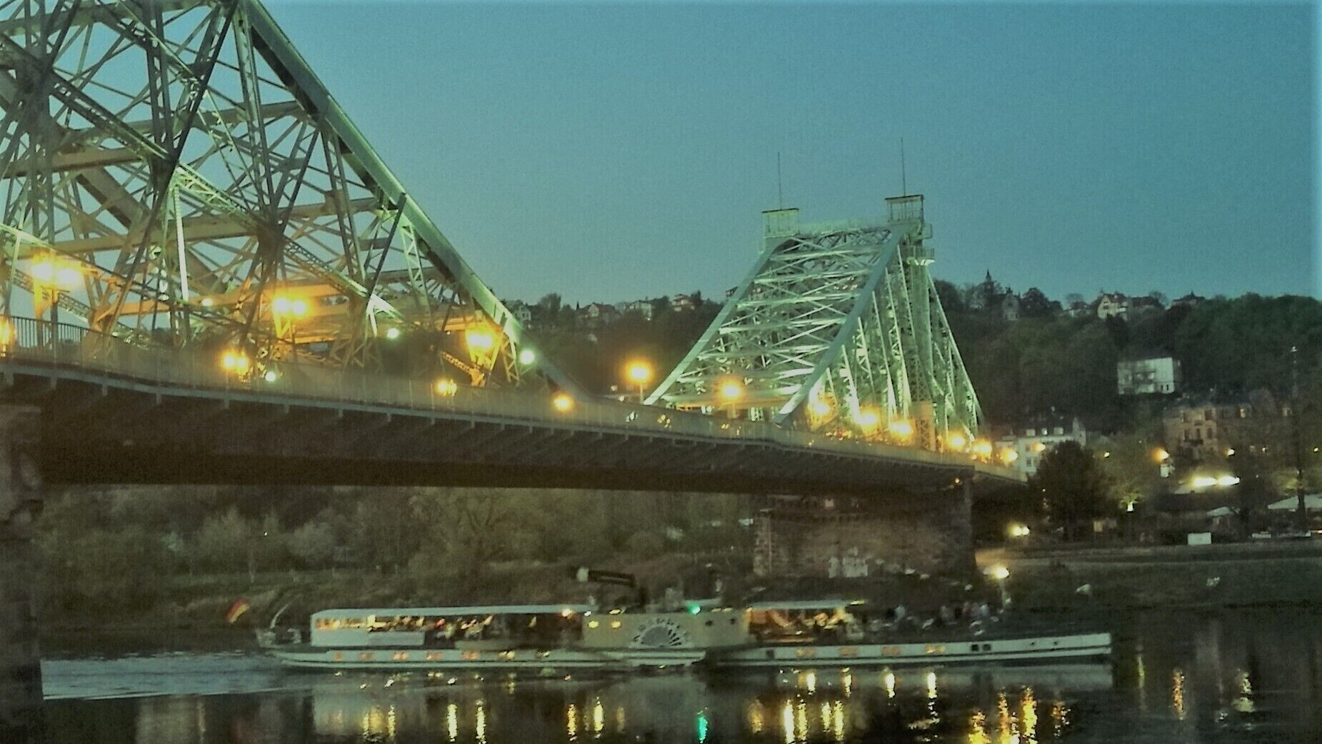 Un pont amb llums il·luminades i una barca a l'aigua.