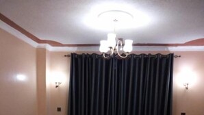 Uma sala de jantar com mesa e cadeiras, um candelabro e cortinas.