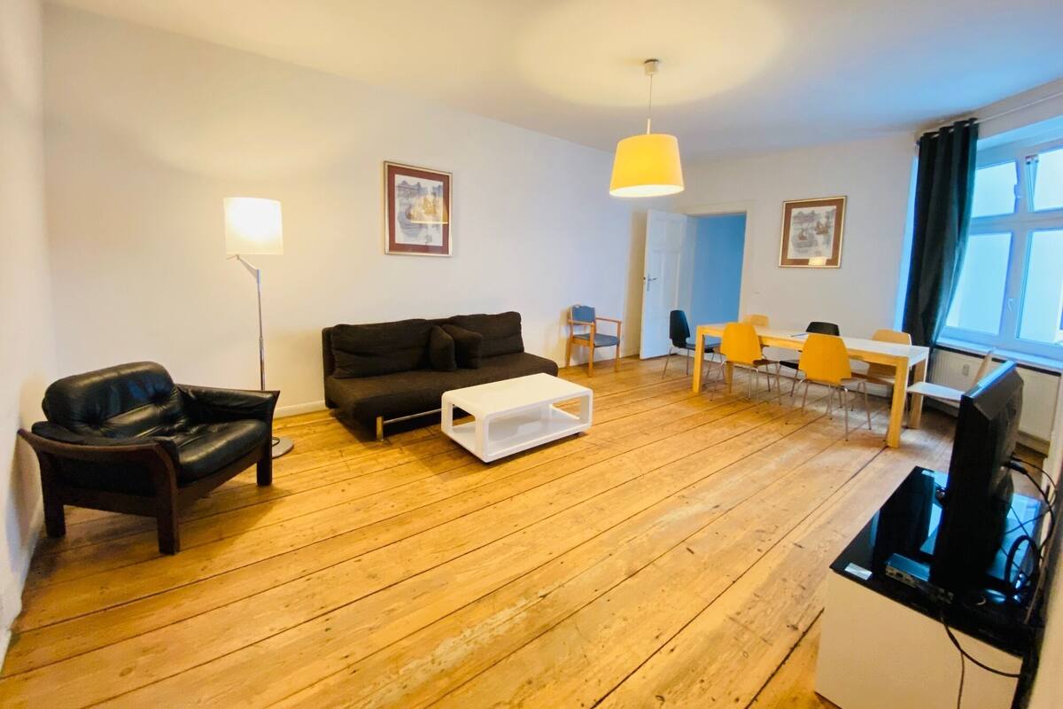 Ein Wohnzimmer mit einer Couch, einem Couchtisch, einem Fernseher und einem Essbereich mit Stühlen und einem Tisch.