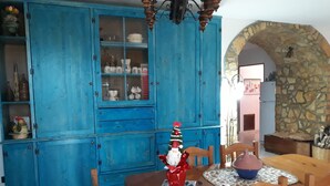 Ein Essbereich mit Holztisch und -stühlen, einem blauen Schrank mit Glastüren sowie einer Steinwand.