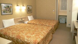 Una habitación de hotel con dos camas, un escritorio, un televisor y un pequeño armario.