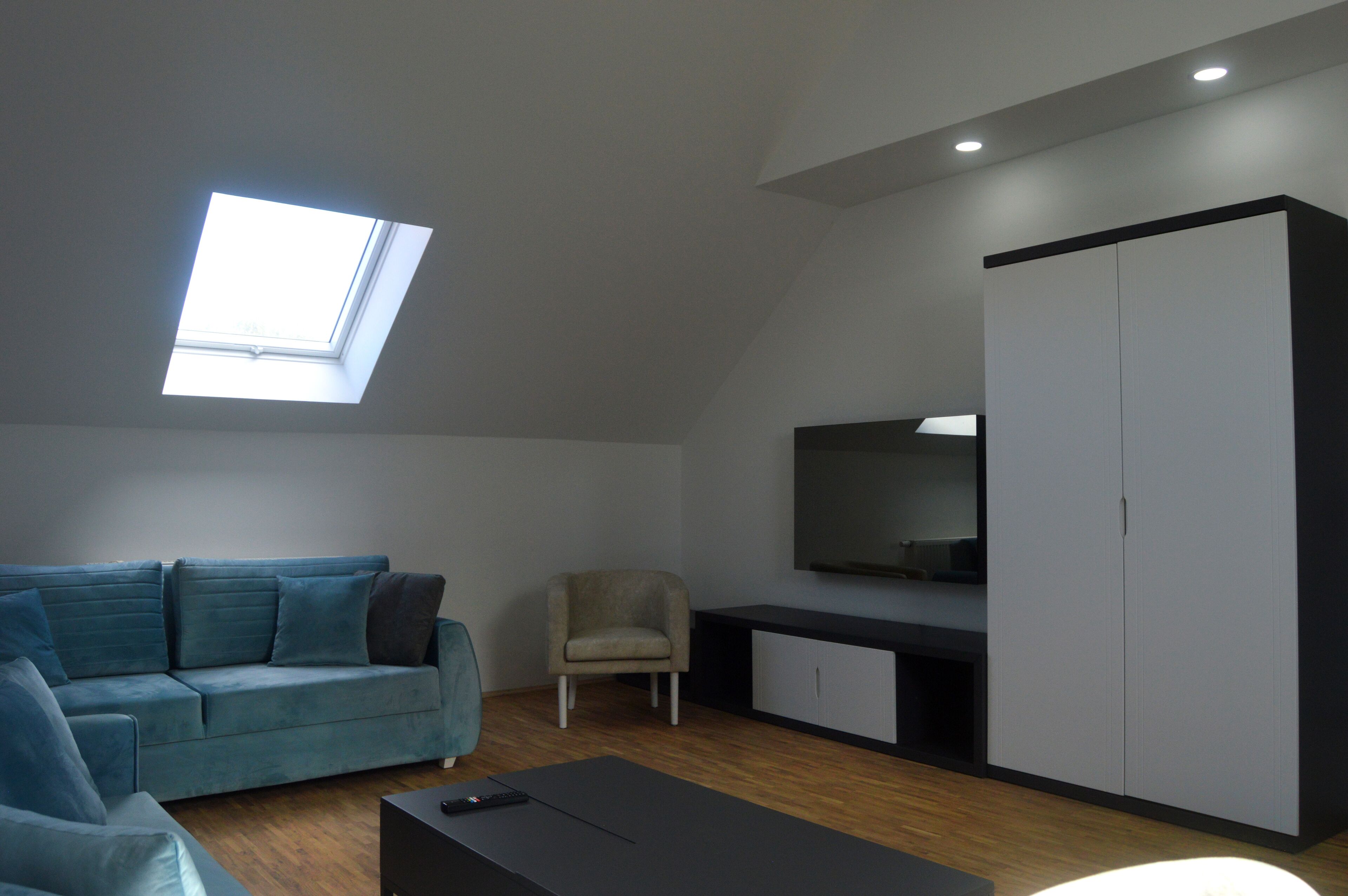 A modern living room with a sofa, a chair, a coffee table, a TV, and a wardrobe.