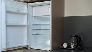 A kitchen with a white refrigerator, a coffee maker, and a small white container on the counter.