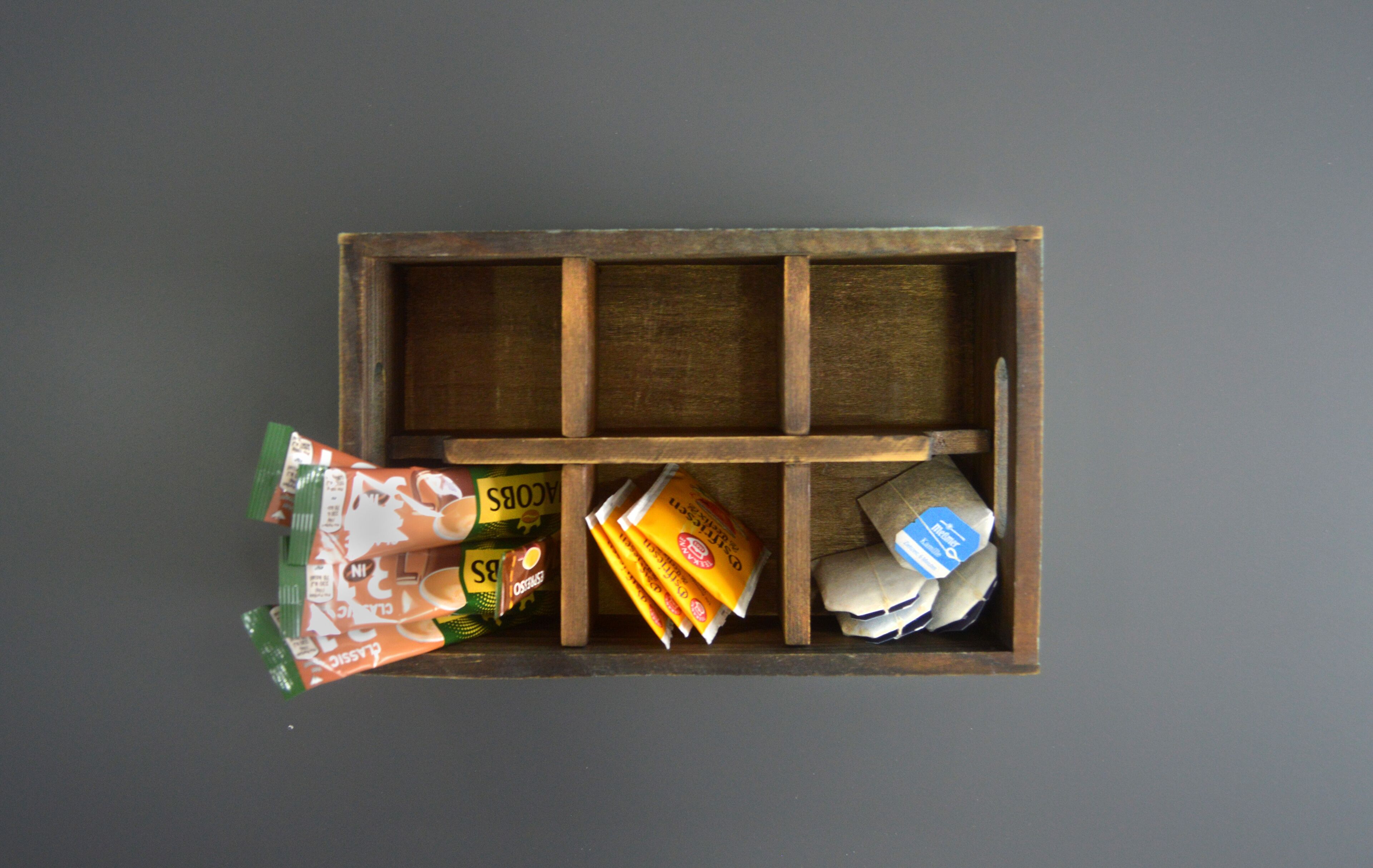 Una caja de madera con compartimentos que contienen diversos artículos envasados.