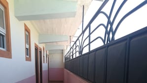 A long corridor with a tiled floor, a metal railing on one side, and doors on the other. - New Journa Complex Hotel (Naro Moru)