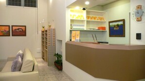 A reception area with a counter, shelves with items, a clock, and framed pictures on the wall. - Family Lodge Hatagoya Iga (Iga)