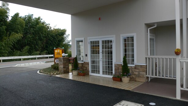 A building with a covered entrance, stone pillars, and potted plants. - Family Lodge Hatagoya Iga (Iga)