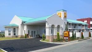 A hotel with a green roof, a prominent clock tower, and a sign indicating the entrance.