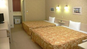 A hotel room with two single beds, a small desk, a television, and a refrigerator.
