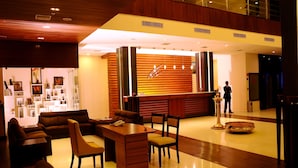 A lobby with a reception desk, seating area, and a display of items. - Holiday Vista (Peermade)