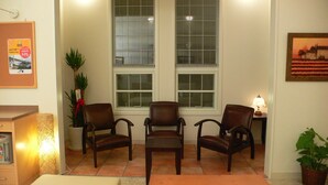 A room with three wooden chairs arranged in a semi-circle, a small table with a lamp, a potted plant, and a framed picture on the wall. - Family Lodge Hatagoya Toki (Toki)