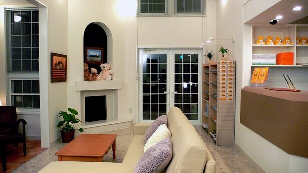 A living room with a fireplace, a sofa, a coffee table, and a bookshelf with books and decorative items. - Family Lodge Hatagoya Toki (Toki)