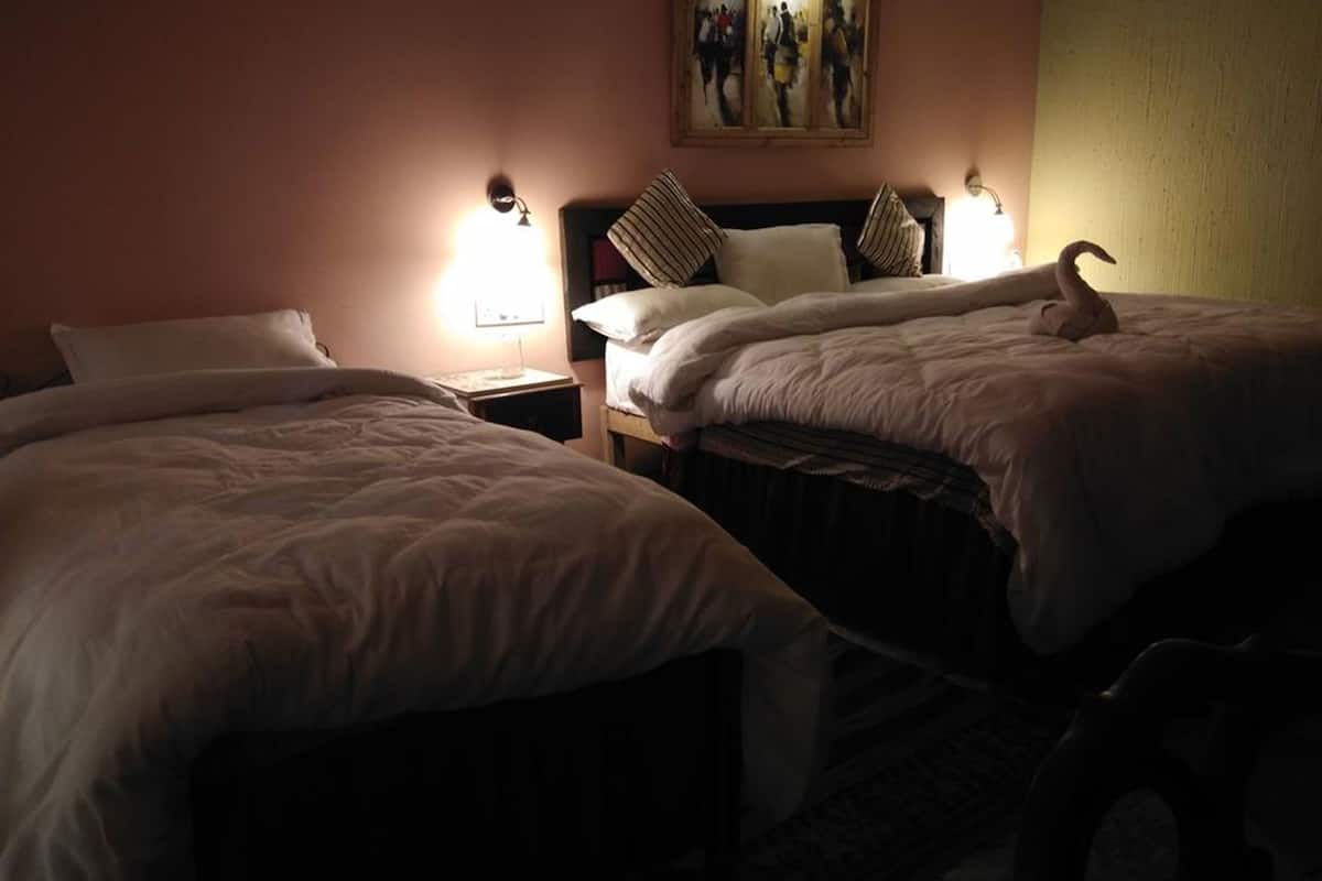 Ein Hotelzimmer mit zwei Betten, jeweils mit Kissen und einer Lampe.