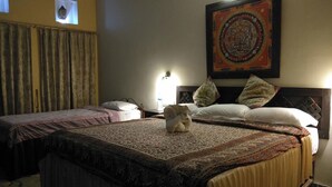 A hotel room with two beds, a large rug, a Buddha statue, and a decorative wall hanging. - Hotel Mountain Ridge (Badharamal)