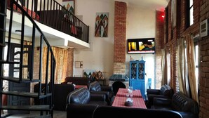 A cozy interior with a staircase, leather seating, a brick fireplace, and a television. - Hotel Mountain Ridge (Badharamal)