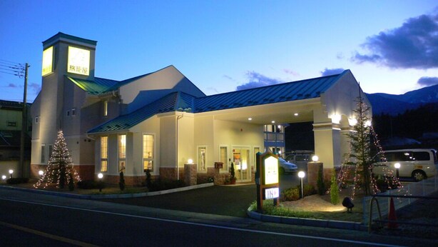 A hotel with a prominent tower, a covered entrance, and Christmas trees. - Family Lodge Hatagoya Nirasaki (Nirasaki)