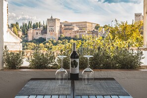 Un tavolo con una bottiglia di vino e due bicchieri, con vista su un centro storico ricco di edifici e aree verdi.