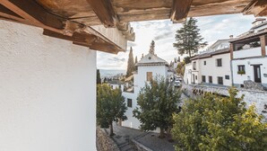Blick vom Balkon mit Holzboden auf eine Stadt mit weißen Gebäuden und einer Kirche mit Glockenturm.
