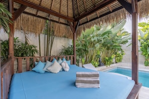 A bed with blue bedding, pillows, and a folded towel.