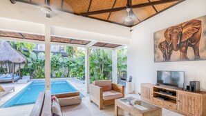 Amplia sala de estar con piscina, asientos cómodos y un televisor grande sobre un mueble de madera.
