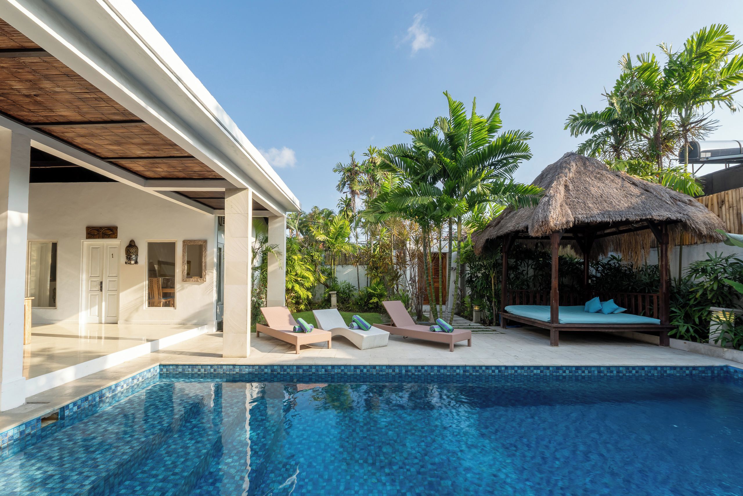 A poolside area with lounge chairs and a thatched-roof structure.