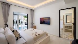 Ein modernes Schlafzimmer mit einem großen Bett, einem Gemälde, einem Badezimmer mit Waschbecken und Blick auf einen Pool.