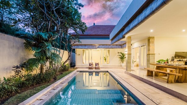 Une maison moderne dotée d’une piscine, d’un coin repas et d’une terrasse couverte.