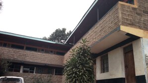 Un edificio de ladrillo con una escalera que lleva a una puerta y un vehículo blanco estacionado.