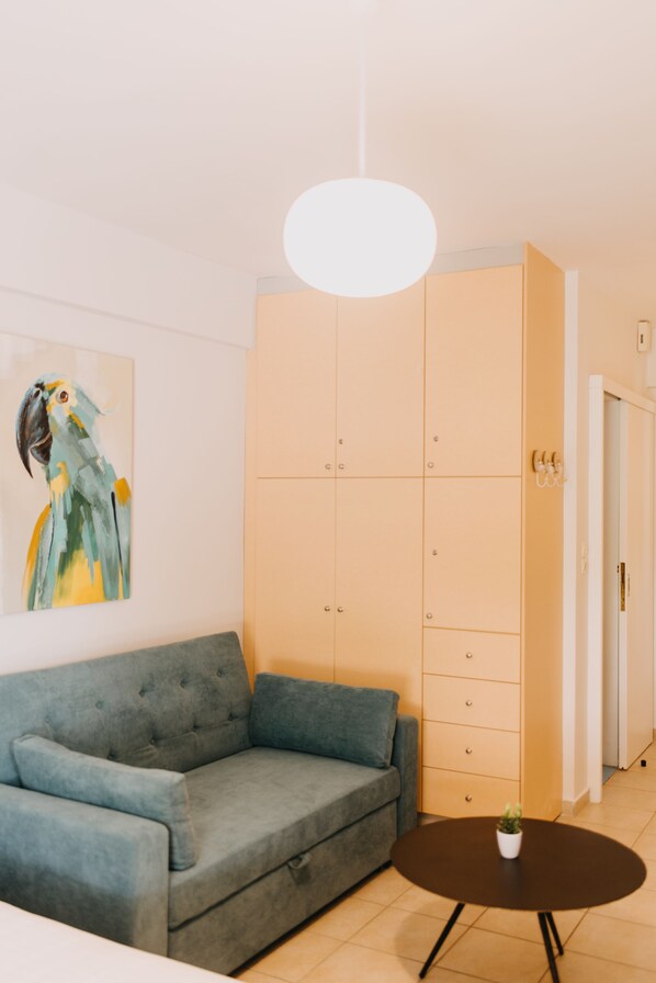 Un salón moderno con un sofá gris, una mesa de centro redonda y un armario grande.