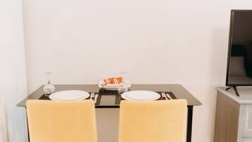 Een eettafel met twee stoelen, een dienblad met oranje voorwerpen en een glas op tafel.