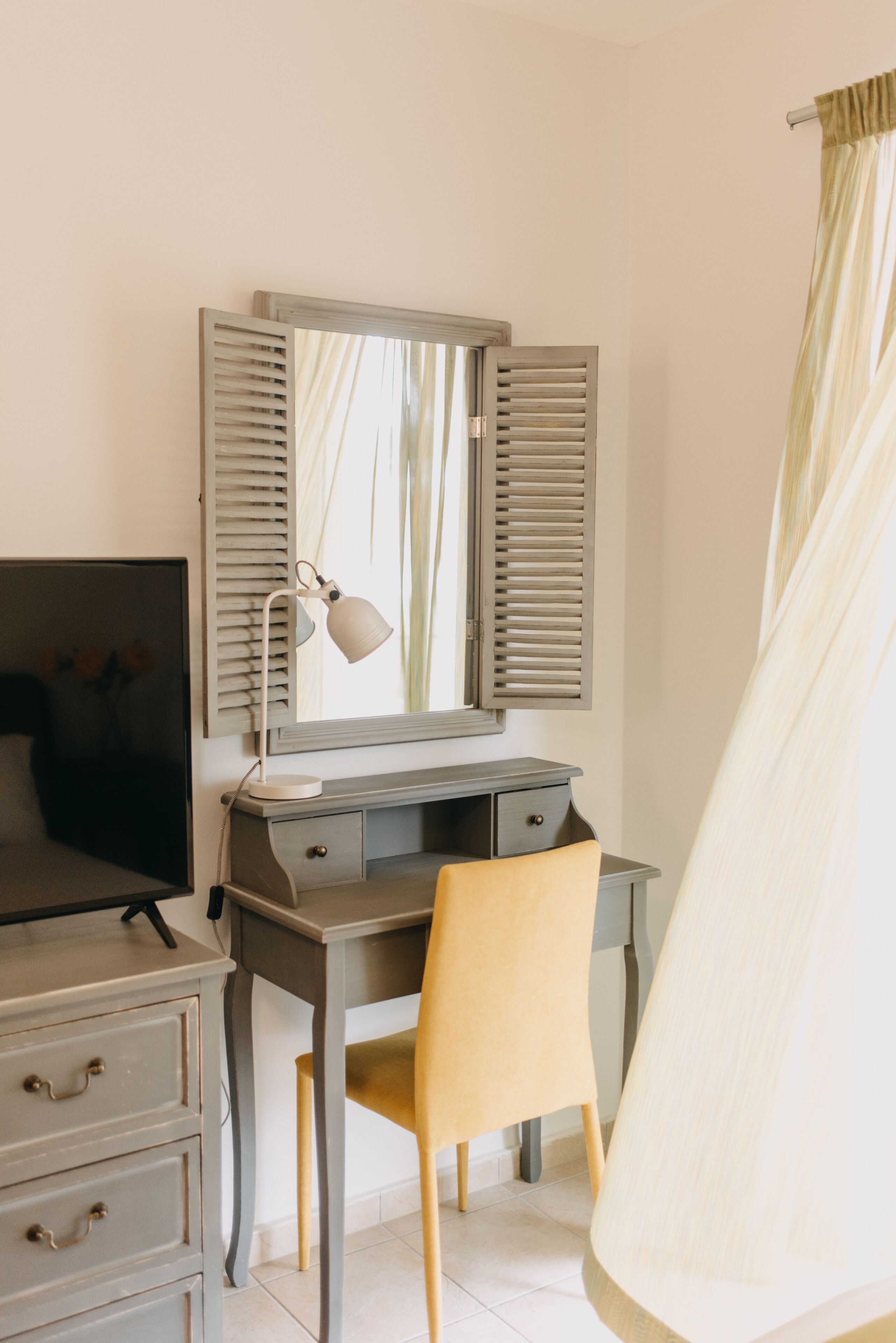 Un dormitorio con una cama, un escritorio con silla, una lámpara y un espejo.