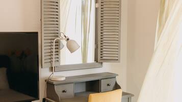 Un dormitorio con una cama, un escritorio con silla, una lámpara y un espejo.