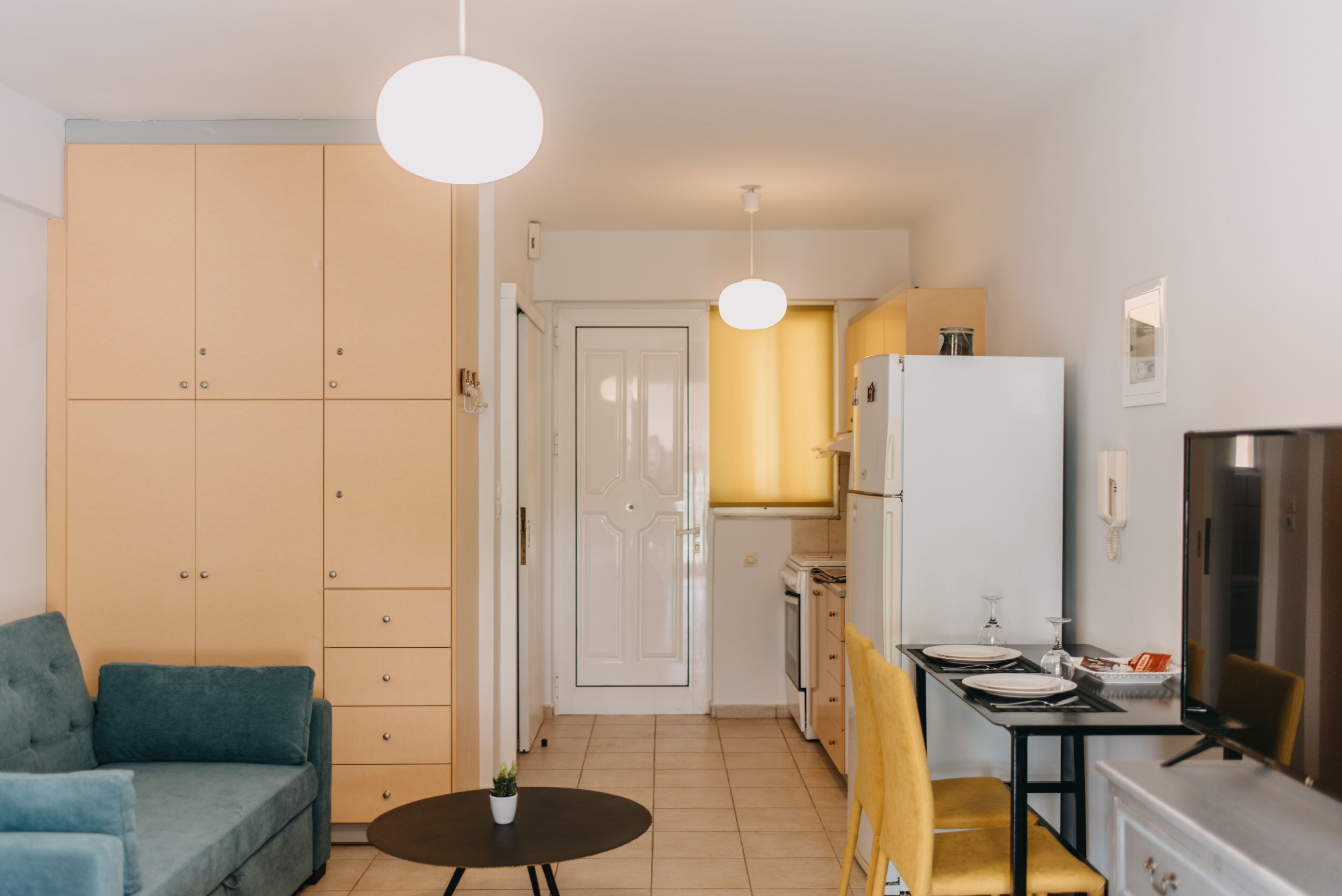 Ein gemütlicher Wohnraum mit Sofa, Esstisch für zwei Personen, Küchenzeile und Fernseher.