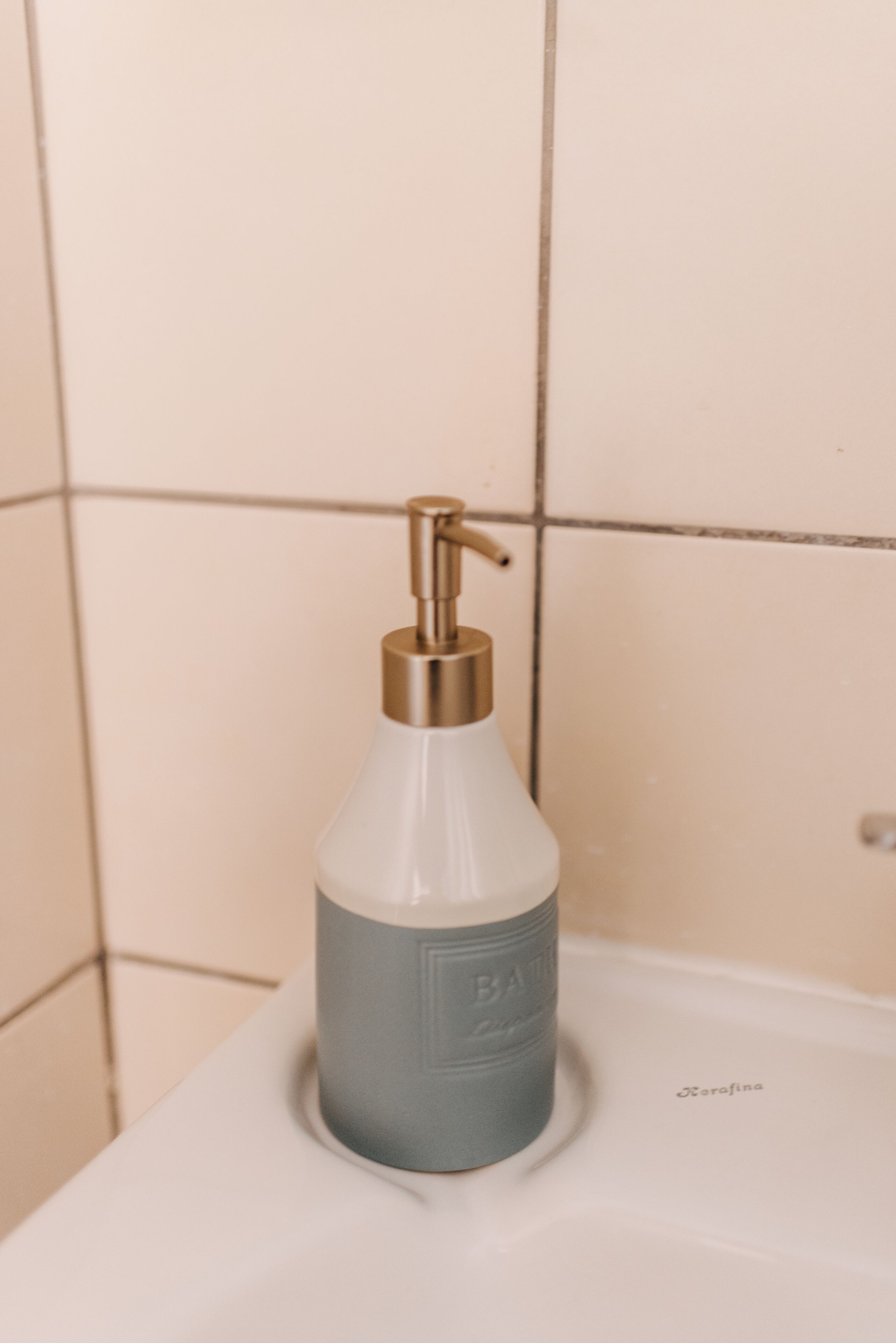 A bathroom with a white sink and a soap dispenser on it.