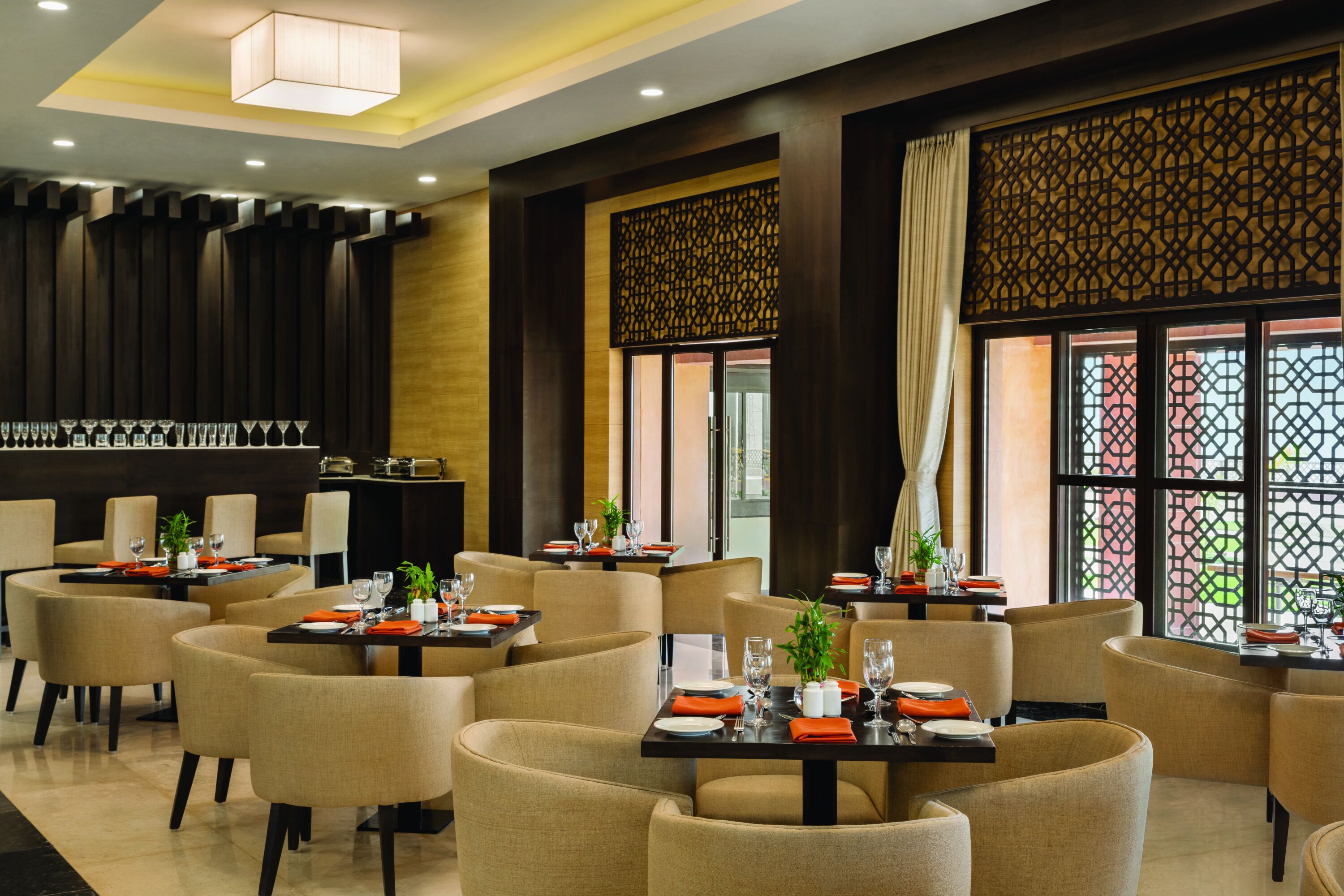 A modern restaurant with multiple tables and chairs, a bar area, and decorative screens.
