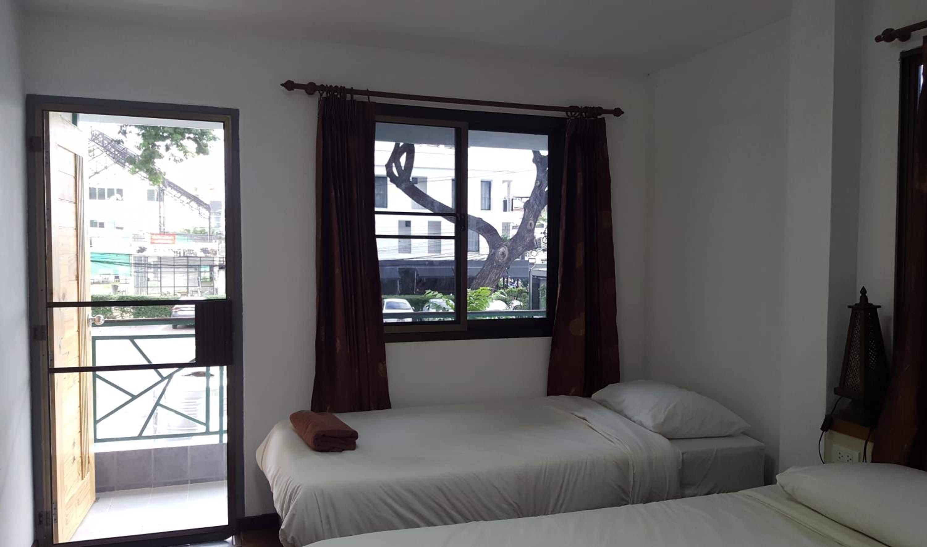 Una habitación con dos camas, una ventana con cortinas y vistas a edificios.