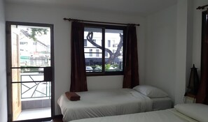 A room with two beds, a window with curtains, and a view of buildings outside. - Aunt & Uncle's House (Chiang Mai)