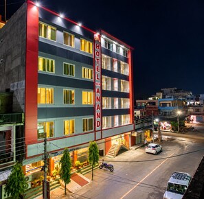 A multi-story hotel with a prominent vertical sign indicating its name. - Hotel New Anand (Bhimdatta)