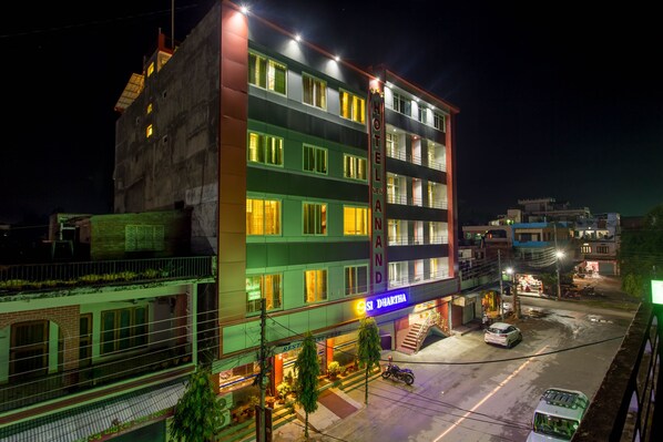 A multi-story hotel with a sign for 'Hotel Anand' and 'SI Dihratha' restaurant.