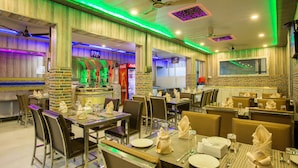 A restaurant with booths and tables, a bar area, and a seating area with a view of the city.