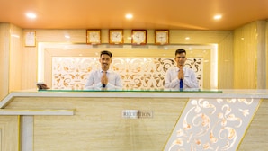A reception desk with two staff members, a clock, and a 'RECEPTION' sign.